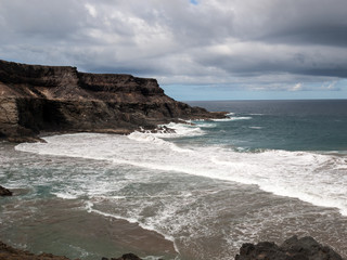 Fototapeta na wymiar Wave splashing over a rock on the beach of Puertito de los Molinos on Fuerteventura. Canary Island, Spain