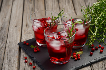Refreshing drink with cranberries and rosemary on wooden background, selective focus, copy space