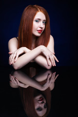 Naklejka premium Young woman with ginger hair over reflection mirror on blue back