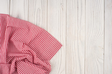 Red folded tablecloth over bleached wooden table.