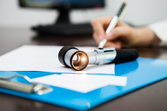 The doctor writes out a prescription for background included Dermatoscope