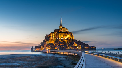 Mont saint michel Illuminated architecture panoramic beautiful postcard view at Dusk in Summer Low Tide from the bridge with reflection, France - obrazy, fototapety, plakaty