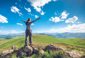 woman with raised hands on hills