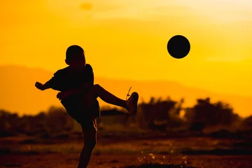 Foto op Aluminium boy is playing football in the sunshine day. © nateejindakum