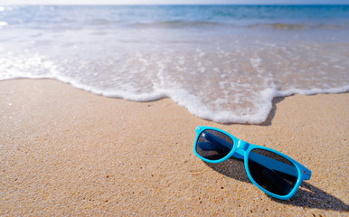 Fototapeta na wymiar Vacation concept. Blue sunglasses on the sea beach.