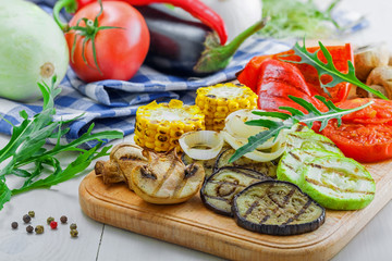 Grilled vegetables meal and ingredients on a table. Tomato, corn, eggplant, mushroom, bell pepper, marrow and onion prepared on a barbecue. Healthy food.