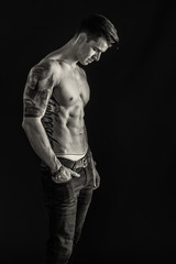 Fototapeta na wymiar Tätowierter Mann im Seitenprofil in schwarz weiß - Junger Mann mit Tattoos und Sixpack 
