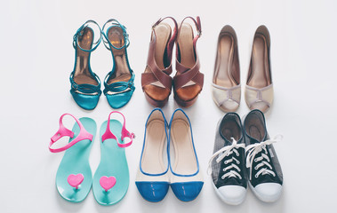 Every girl needs. Overhead of essentials for modern young woman. Different ladies shoes on white wooden background.