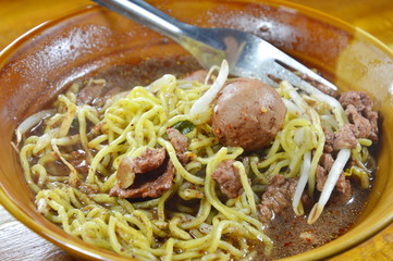 egg noodle with pork ball in brown soup on bowl