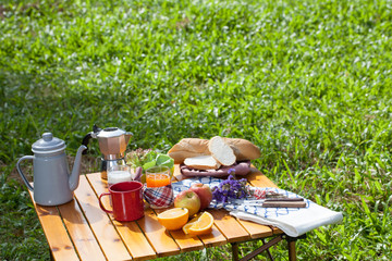 full picnic table with pancake on iron pan and fruit and coffee cup and jug