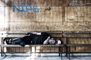 Homeless Man Sleeping on the Wooden Bench in the Train Station - 121455010