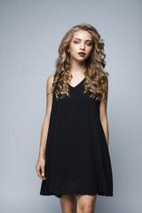 Fototapeta premium Beautiful girl in a black dress in the studio on a white backgro