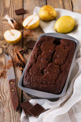 .Chocolate cake with pears and cinnamon on old wooden background. Selective focus.