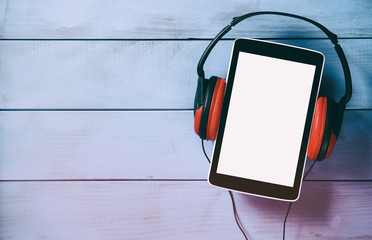 top view of tablet and headphones over wooden table