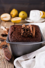 .Chocolate cake with pears and cinnamon on old wooden background. Selective focus.