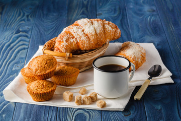 cup of black coffee in an old enamel mug, breakfast croissants o