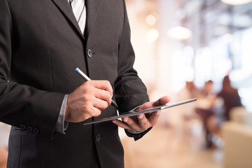 Business man working with a digital tablet on abstract blurred people background, success and profitable business concepts
