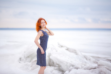 Fototapeta na wymiar Red-haired girl dressed in a dress in the snow