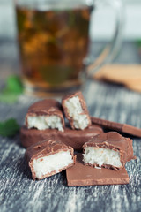 Cup of tea on a wooden background. Hot mint tea with chocolate, candy and cookies on old table