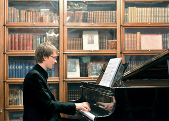 Young man playing on black grand piano