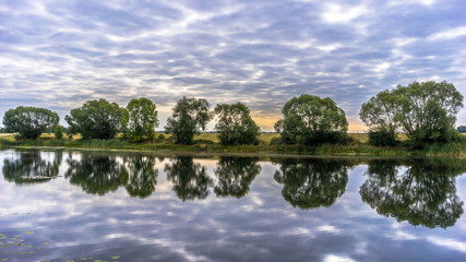 Beautiful panoramic landscape, cloudy sky, trees and water