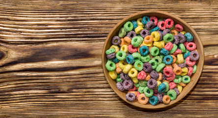 wooden bowl with colorful cereal on wooden background