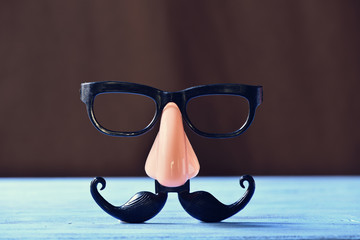 fake mustache, nose and eyeglasses on a blue surface