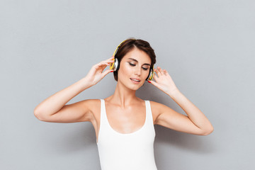Fototapeta premium Beautiful brunette young woman listening to music with headphones