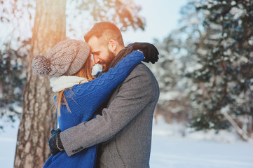 happy loving couple walking in snowy winter forest, spending christmas vacation together. Outdoor seasonal activities. Lifestyle capture.