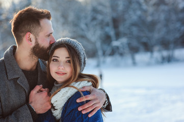 happy loving couple walking in snowy winter forest, spending christmas vacation together. Outdoor seasonal activities. Lifestyle capture.