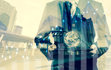 Double exposure of success businessman using digital tablet with graph on the business city centre. A metaphor of international financial consulting.(Elements of this image furnished by NASA)