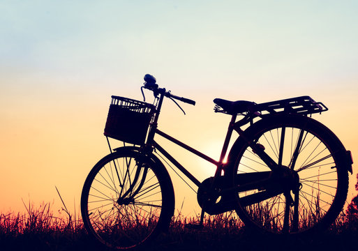 beautiful landscape image with silhouette Bicycle at sunset