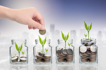 Fototapeta na wymiar Hand putting money coins and seed in clear bottle on cityscape photo blurred cityscape background,Business investment growth concept