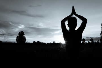Silhouette of man practicing yoga with beautiful sunset