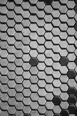 Metal hexagons texture in wall. Some lighter and other darker because of different reflections. Black and white. Architecture detail.