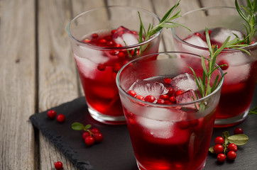 Refreshing drink with cranberries and rosemary on wooden background, selective focus