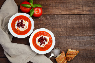 Tomato cream soup with beans on wooden background, top view, copy space