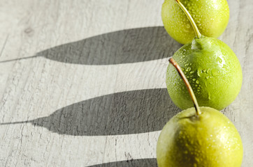 Three juicy green pear with water drops cast a long shadows on  bright wood background 
