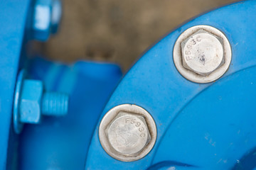 Close-up detail of shiny metal screws on blue gas pipes. Oil and gas industry concept.