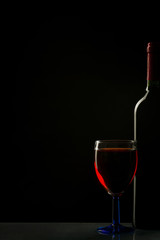 Glass and bottle of wine isolated on a black background
