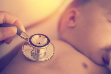 Pediatric doctor exams newborn baby girl with stethoscope in hos