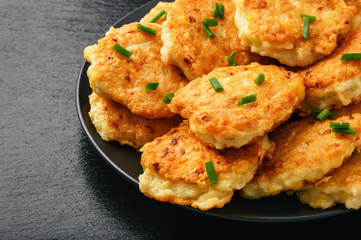Roasted chicken cutlets with garlic and cheese on black background.
