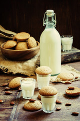 Cow's milk in the bottle and a glass and cookies with almond ama