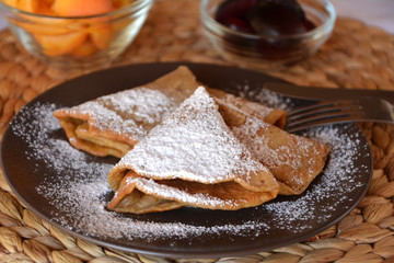 Homemade pancakes with jam and icing sugar.