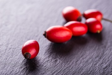 Several red hips placed on black slate stone
