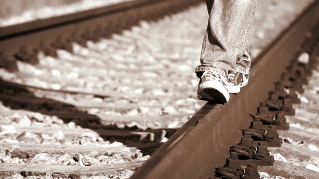 Footage turns colorful: a person walks along railway wearing sneakers