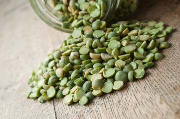 détail pois cassés tombant d'un bocal de verre sur fond en vieux bois