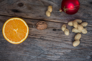 Weihnachtshintergrund: Orange, Nüsse und Christbaumkugel auf Holzuntergrund