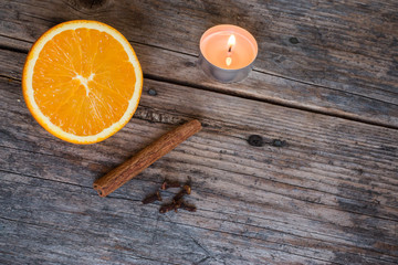 Weihnachtshintergrund: Orange, Zimt, Nelken und Teelicht auf Holzuntergrund