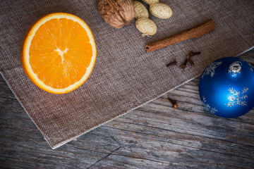 Weihnachtshintergrund: Orange, Zimt, Nelken und Christbaumkugel auf Holzuntergrund